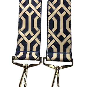 May include: Two gold-colored clasps with blue and beige patterned straps. The straps have a geometric design.