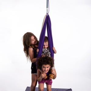 Kids playing with purple and cream restNest sensory swing chair with spring suspension, indoor hammock swing for active play and calming movement, Montessori-inspired kids room decor made from soft cotton fabric for sensory regulation and cosy relaxation.