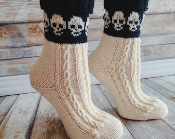 Könnte beinhalten: Ein Paar cremefarbene Stricksocken mit schwarzen Totenkopfmotiven am Bündchen. Die Socken sind aus einem weichen, bequemen Material gefertigt und haben ein Zopfmuster.