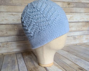 May include: A light blue knitted beanie with a textured pattern. The beanie is on a wooden surface.