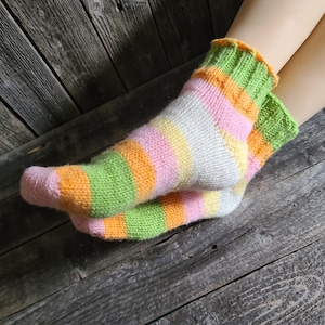 Peut inclure: Une paire de chaussettes rayées en rose, vert, orange et blanc. Les chaussettes sont tricotées et ont un bord côtelé.