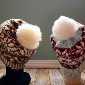 May include: Two knitted hats with white pom-poms. The hat on the left is green, white, and red. The hat on the right is blue, white, and red.