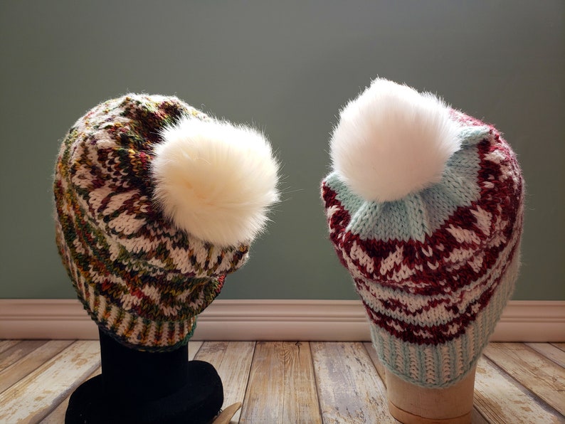 May include: Two knitted hats with white pom-poms. The hat on the left is green, white, and red. The hat on the right is blue, white, and red.