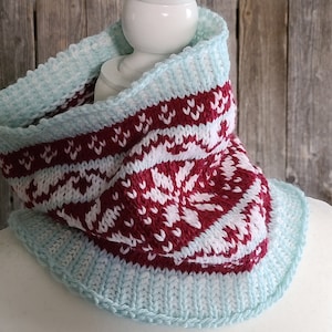 Puede incluir: Un cuello de punto con un patrón de copo de nieve blanco y burdeos y un borde azul claro.