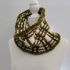 May include: A green and white knitted infinity scarf with a textured pattern. The scarf is displayed on a white mannequin.