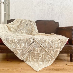 Può includere: Una coperta in crochet bianco con un delicato motivo floreale drappeggiata su un divano in pelle marrone.