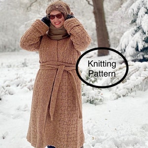 May include: A brown knitted coat with a belt, worn by a person in a snowy landscape. The coat has a textured pattern and a high collar. The person is wearing a brown hat and sunglasses.