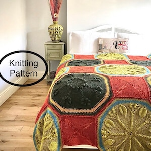 May include: A knitted throw blanket with a geometric pattern in shades of green, red, and yellow. The blanket is on a bed with white bedding and a pillow with the word "LOVE" on it.