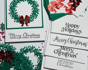 May include: Christmas cards featuring green wreath and red bow designs. Some cards have the text "Merry Christmas" and "Happy Holidays". Other cards have the text "Thinking of you at Christmas" and "Seasons Greetings".