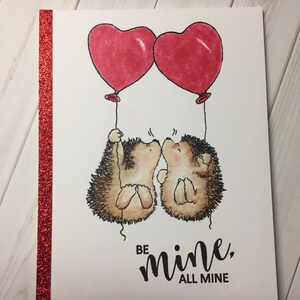 Puede incluir: Una tarjeta de San Valent&iacute;n con dos erizos sosteniendo globos en forma de coraz&oacute;n. La tarjeta dice "S&eacute; m&iacute;o, todo m&iacute;o".