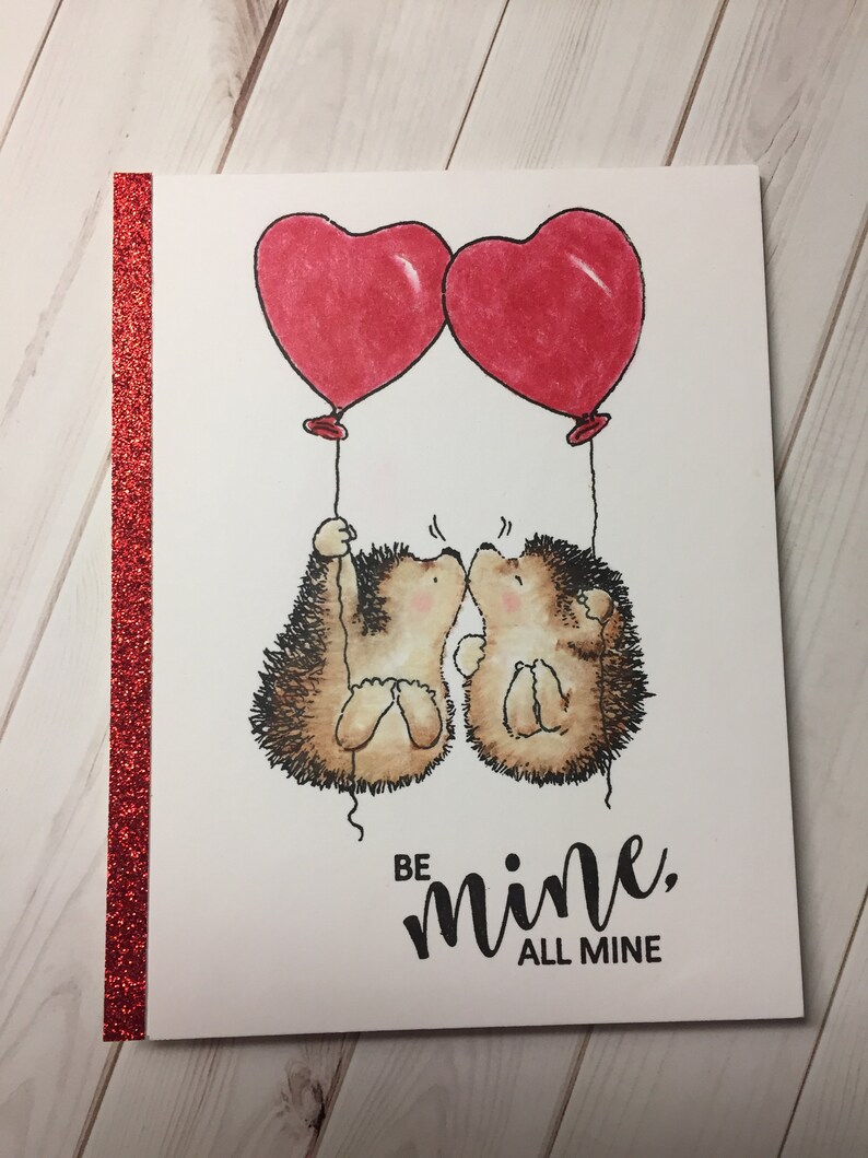 Puede incluir: Una tarjeta de San Valent&iacute;n con dos erizos sosteniendo globos en forma de coraz&oacute;n. La tarjeta dice "S&eacute; m&iacute;o, todo m&iacute;o".