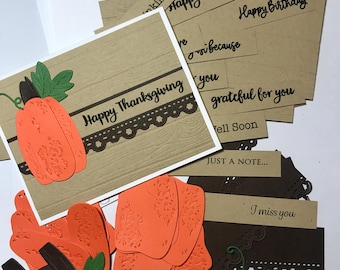 May include: A set of brown cardstock cards with a pumpkin design and various messages, including "Happy Thanksgiving", "Just a Note", and "I miss you". The cards are decorated with brown and white lace trim and green leaves.