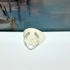 May include: A silver ear cuff with a hammered texture. The cuff is shaped like a V and has a simple design.