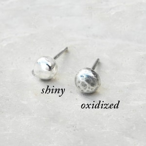 May include: Two silver stud earrings, one with a shiny finish and the other with an oxidized finish. The earrings are labeled "shiny" and "oxidized".