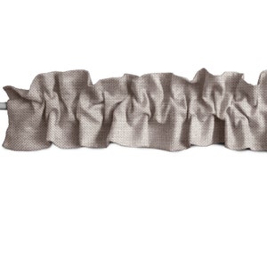 May include: A brown fabric valance with a ruffled edge. The valance is made of a textured fabric and is perfect for adding a touch of elegance to any window.