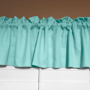 May include: A light blue valance with a ruffled edge. The valance is hanging over a white window blind.