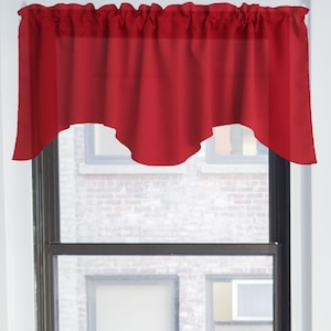 May include: Red valance with a scalloped edge, hanging in a window.