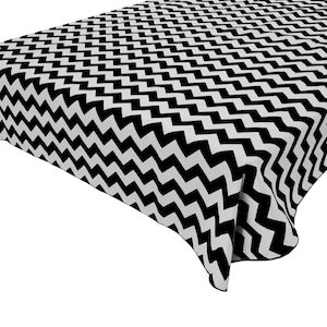May include: Black and white chevron patterned tablecloth. The tablecloth is made of a soft, smooth fabric and has a subtle sheen.