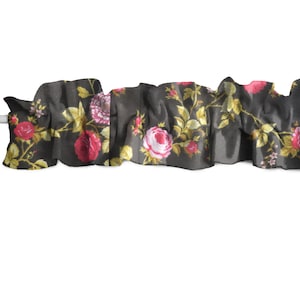 May include: Black fabric with a ruffled edge and a floral print of pink and red roses with green leaves.