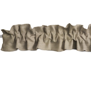 May include: A brown fabric valance with a ruffled edge. The valance is made of a textured fabric and has a slightly distressed look.