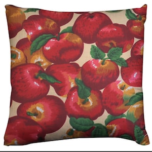 May include: Square throw pillow featuring a repeating pattern of red apples with green leaves on a beige background. The apples vary in size and have highlights, creating a textured appearance. This decorative pillow adds a touch of nature to any room.