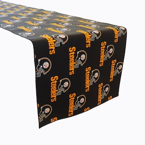 May include: Black table runner with a repeated pattern of the Pittsburgh Steelers logo. The logo is a black helmet with a yellow star and the word "Steelers" in orange.