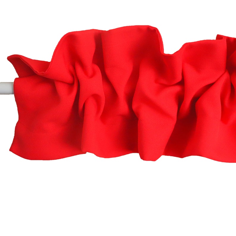 May include: A bright red fabric valance with a ruffled edge. The valance is gathered and draped, creating a soft and flowing look.