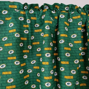 May include: Green and white fabric valance with a repeating pattern of the Green Bay Packers logo and the word "Packers".