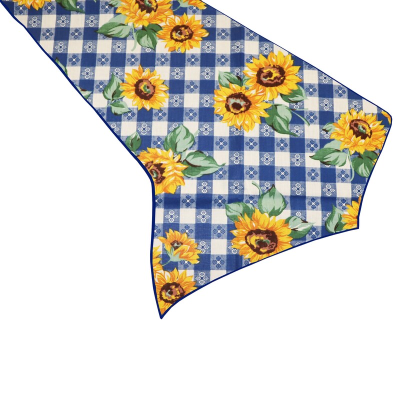 Op de afbeelding: Een decoratieve tafelloper met een blauw-wit ruitpatroon, versierd met gele zonnebloemen en groene bladeren. De loper heeft een donkerblauwe rand en is ontworpen om een vleugje rustieke charme toe te voegen aan elke eettafel.
