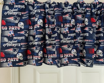 Pode incluir: Uma valance de tecido azul e vermelho com um padrão repetido do logotipo do New England Patriots, bolas de futebol e as palavras "Go Pats" e "New England Patriots".