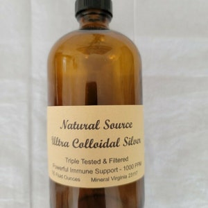 May include: A brown glass bottle with a black cap, labeled "Natural Source Ultra Colloidal Silver". The label also states "Triple Tested & Filtered", "Powerful Immune Support - 1000 PPM", "16 Fluid Ounces", and "Mineral Virginia 23117".
