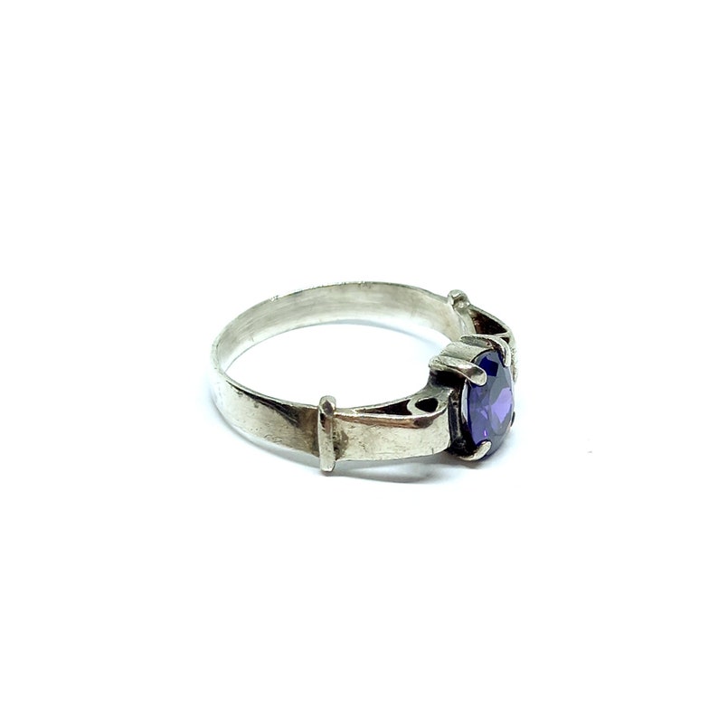 May include: A silver ring with a purple gemstone set in a decorative setting.