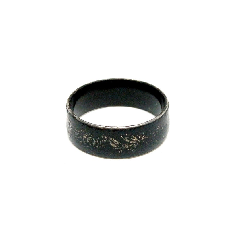 K&ouml;nnte beinhalten: Ein schwarzer Metallring mit einem dekorativen Design. Der Ring ist schlicht und elegant.