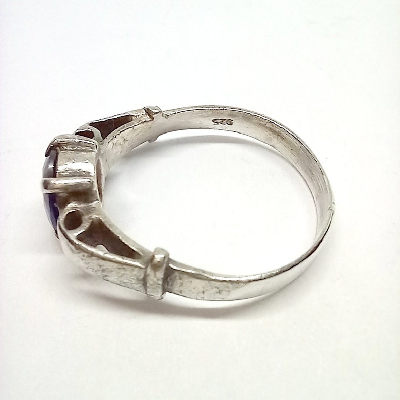 May include: A silver ring with a blue gemstone set in a decorative setting. The ring is marked "925" on the inside band.