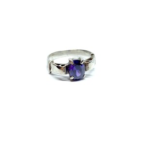 May include: A silver ring with an oval-shaped purple gemstone set in the center.