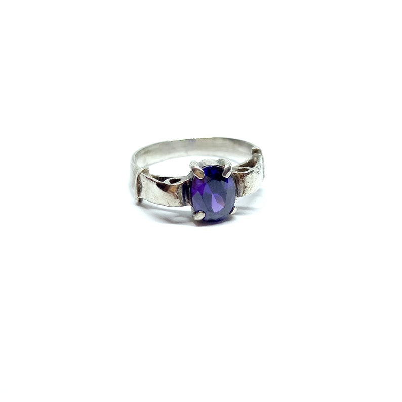 May include: A silver ring with an oval-shaped purple gemstone set in the center.