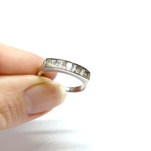 May include: A silver band ring with a row of clear cubic zirconia stones.