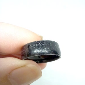 K&ouml;nnte beinhalten: Ein schwarzer Ring mit einer strukturierten Oberfl&auml;che und einem eingravierten Design auf der Band.