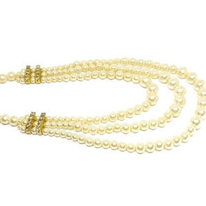 Può includere: Una collana di perle multifilo con una chiusura dorata decorata con strass trasparenti. La collana è realizzata con perle finte ed è uno stile classico.