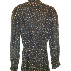 May include: A long-sleeved black dress with a high neck and a floral print. The dress has a fitted bodice and a flowing skirt.