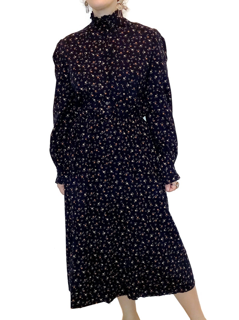 May include: A black midi dress with a floral print. The dress has a mock neck, long sleeves, and a gathered waist.