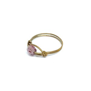 Puede incluir: Un anillo de alambre dorado con una sola cuenta de vidrio púrpura.