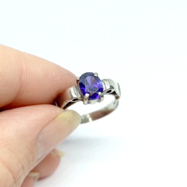 May include: A silver ring with a purple oval gemstone.