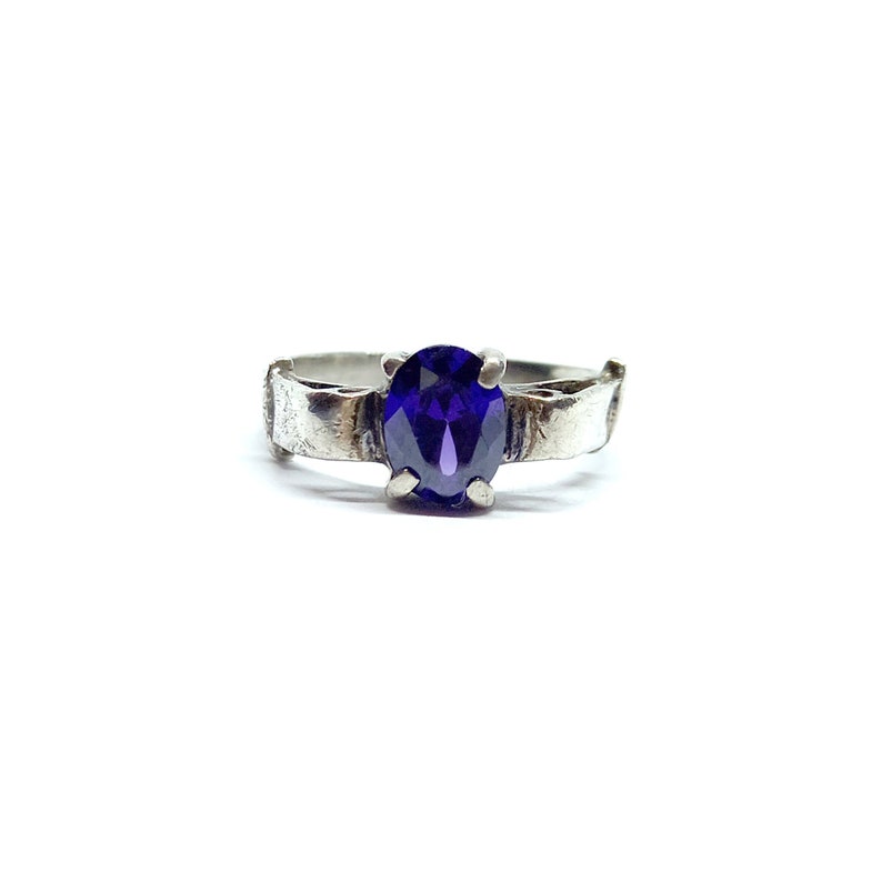 May include: A silver ring with a dark purple oval gemstone.