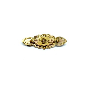 May include: A gold-toned brooch with a floral design. The brooch has three small pink flowers and a swirl design in the center.
