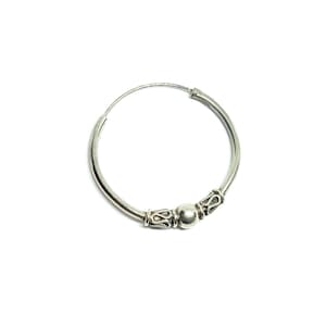 May include: A single silver hoop earring with decorative bead accents. The earring features a small, round bead in the center, flanked by ornate, patterned metalwork. The earring is set against a white background.