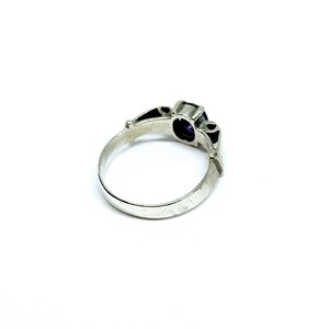 May include: A silver ring with a purple gemstone set in a decorative setting.