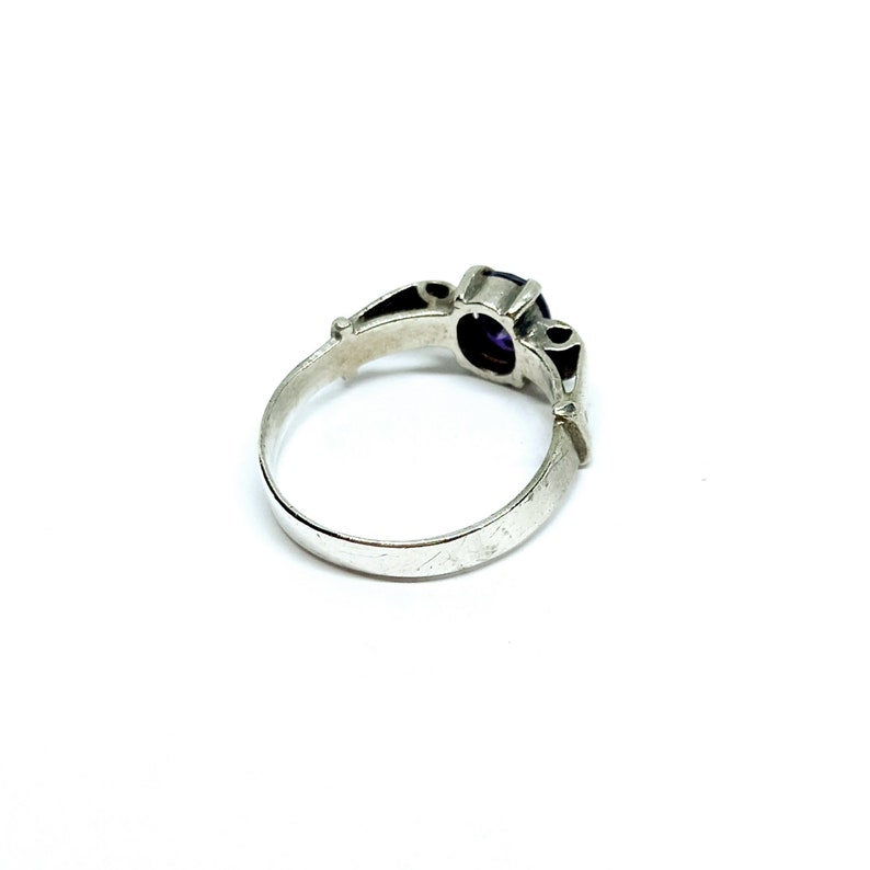 May include: A silver ring with a purple gemstone set in a decorative setting.