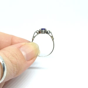May include: A silver ring with a purple gemstone set in a delicate, ornate design.