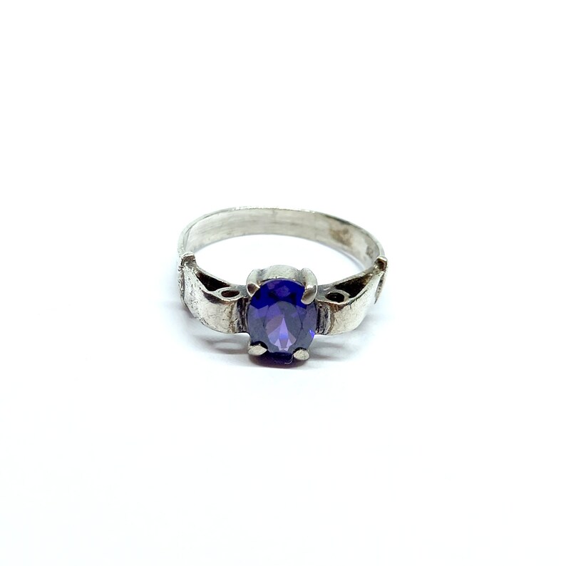 May include: A silver ring with a purple oval-shaped gemstone set in the center.